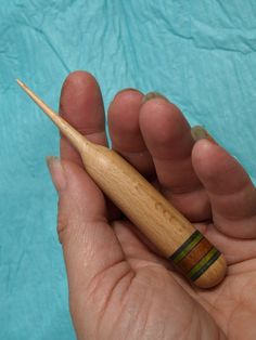 a hand holding a small wooden object in it's left hand, with a toothpick sticking out of it