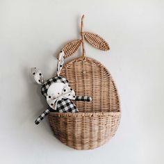 a stuffed animal in a wicker basket hanging on the side of a white wall