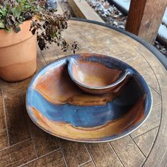 two bowls sitting on top of a table next to a potted plant