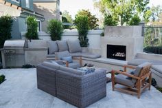 an outdoor living area with couches, chairs and a fire place in the middle