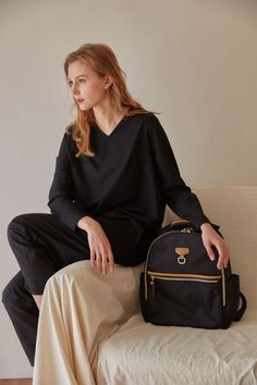 a woman sitting on a couch with a black backpack