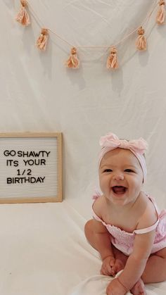 a smiling baby sitting on a bed next to a sign that says go shawty it's your birthday