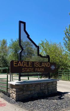 the eagle island state park sign is shown in front of a fenced area and trees