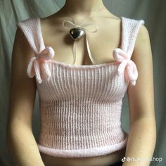 a woman wearing a pink knitted top with a heart shaped object attached to her chest