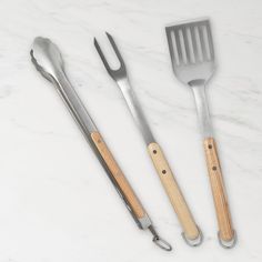 three utensils and a spatula on a marble surface