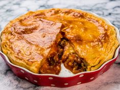 a baked dish with meat and cheese in a red pan on a marble countertop