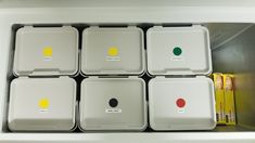 six white containers with yellow and green dots on them in a refrigerator door drawer next to some cereal bars