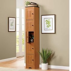 a tall wooden cabinet with drawers in a living room next to a potted plant