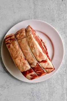 slices of meat sitting on top of a white plate