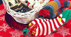 a basket filled with socks on top of a red cloth covered table next to a christmas tree