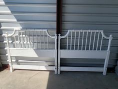 two white benches sitting next to each other in front of a garage door on the side of a building