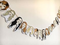 a group of people hanging from a line on a wall with paper cutouts in the shape of faces