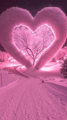 a pink heart shaped tree in the middle of a snow covered road with houses and trees behind it