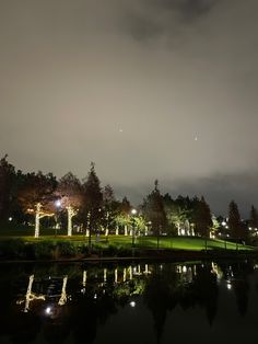 the night sky is lit up with lights and reflecting in the water at the park