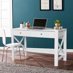 a white desk with a laptop on top of it in front of a blue wall