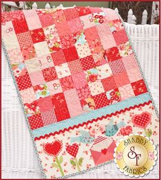 a red and pink patchwork quilt on a white wicker chair with the words happy valentine's day written below it