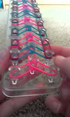 a person is holding a plastic case with colored lines on it and the bottom half of the case has pink, blue, and black buttons