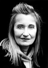 a black and white photo of a woman with long hair wearing a jacket, smiling at the camera