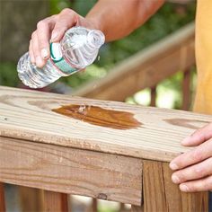 a person pouring water onto a wooden bench with their hand on the top of it