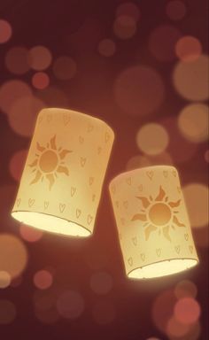 two yellow lamps with hearts and sun designs on them are shining brightly in the dark