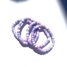 three purple and white bracelets sitting on top of each other next to a blue object