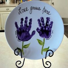 a plate with two handprints on it that says love grows here