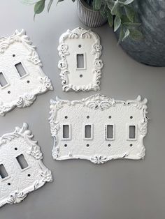 three white switch plates sitting on top of a table next to a potted plant