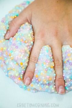 a close up of a person's hand on top of a doughnut covered in sprinkles