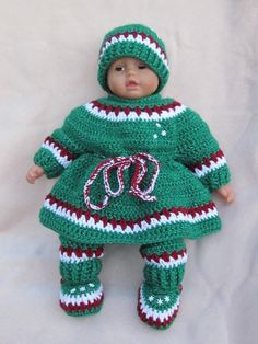 a crocheted doll is wearing a green and red dress with white stripes on it