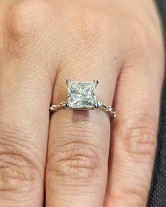 a woman's hand with a diamond ring on top of her finger and an engagement band