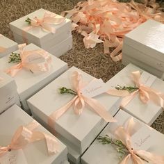 many white boxes with pink bows and ribbons on the floor next to some other boxes