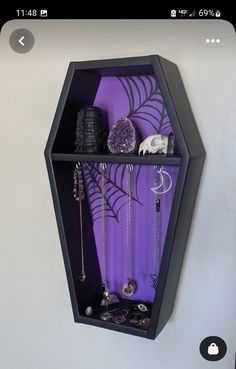 a black hexagonal shelf with jewelry hanging from it's sides on the wall