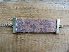 a bracelet with writing on it sitting on top of a piece of wooden planks