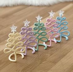 three crocheted christmas tree ornaments on a wood floor