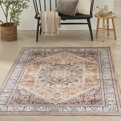 a large rug with an ornate design on the floor next to a chair and potted plant