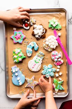 someone decorating decorated cookies on a cookie sheet