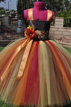 a dress made out of tulle with flowers on the top and bottom, sitting in grass