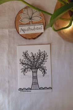 there is a plant on the table next to some coasters that say madhubani