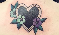 a heart tattoo with flowers and leaves on the back