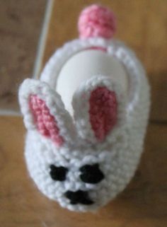 a crocheted white and pink bunny head bottle stopper on a wooden table