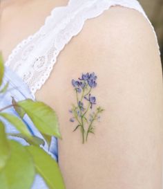 a close up of a person's shoulder with flowers on it and a plant in the foreground