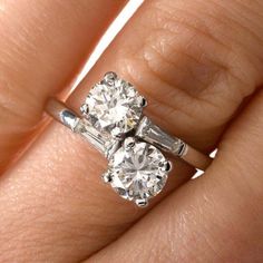 a woman's hand with two engagement rings on it