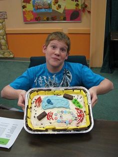 a boy sitting at a table with a cake in front of him