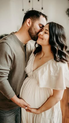 a pregnant couple kissing while standing next to each other