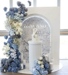 a white and blue wedding cake surrounded by flowers