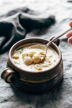 a hand holding a spoon full of soup