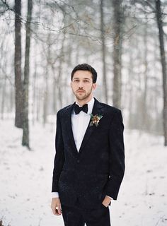 a man in a tuxedo standing in the snow