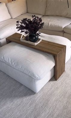 a living room with a couch, ottoman and coffee table in the middle of it