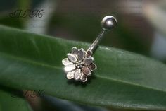 a flower shaped nose ring sitting on top of a green leaf