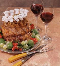 a plate topped with meat and vegetables next to two glasses of wine